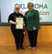 Two women with one holding award.
