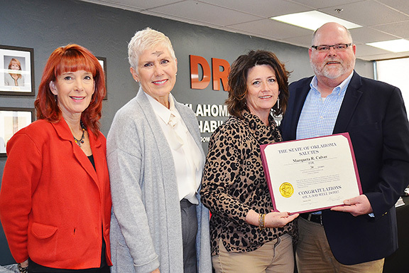 Four people standing with one holding certificate.
