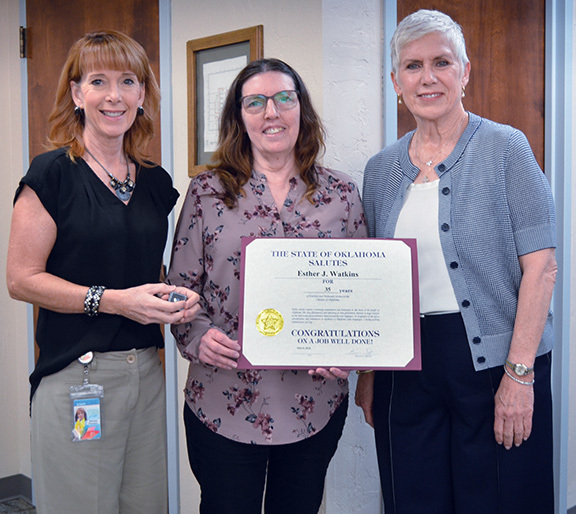 Three woman with one in middle holding a certificate.