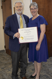 Woman standing next to man holding a certificate.