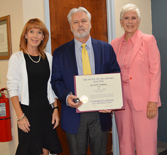 Two women and one man holding a certificate.
