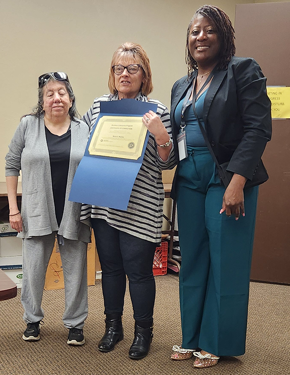 Three women with one holding a certificate.