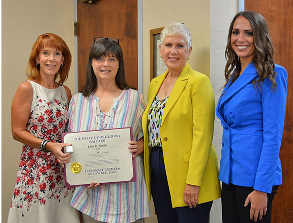 Four women with one holding a certificate.
