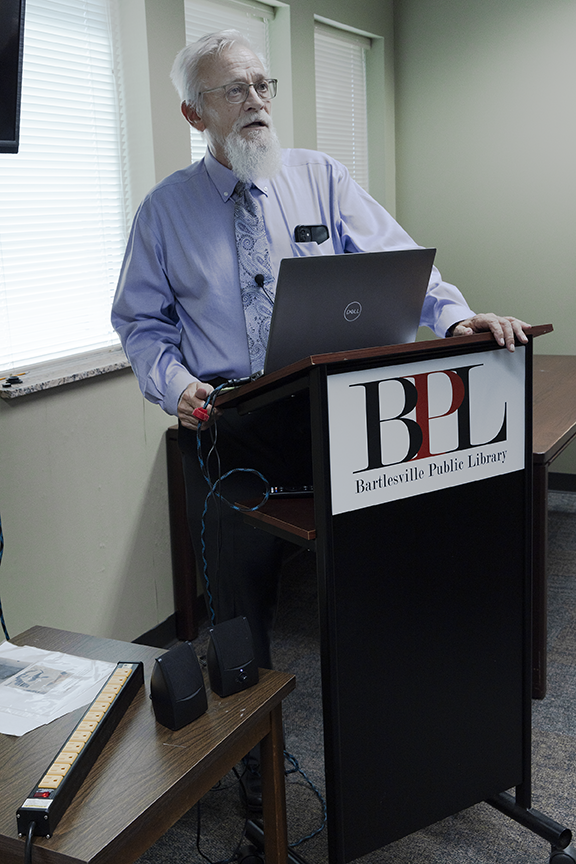 Man with beard speaking from behind podium.