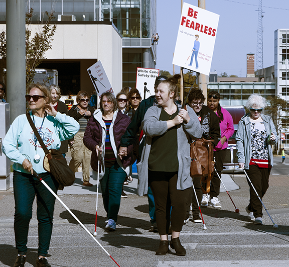 People walking through downtown Tulsa. Some are using using white canes.