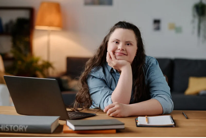 a student is sitting at a table with a laptop and notebook