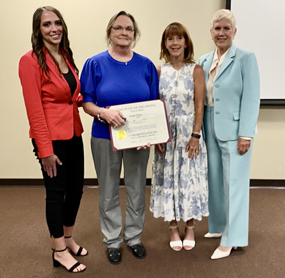 Four women with one holding a certificate.