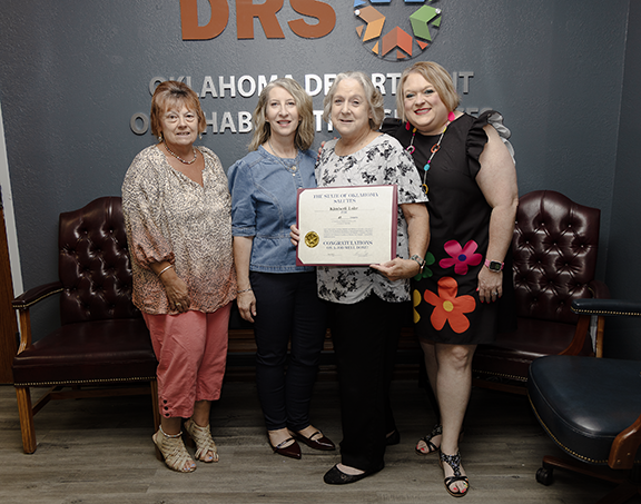 Four women with one holding a certificate.