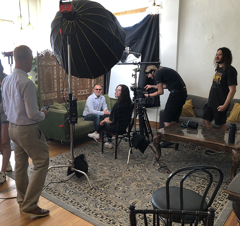 Group of people in room with video camera and lights.