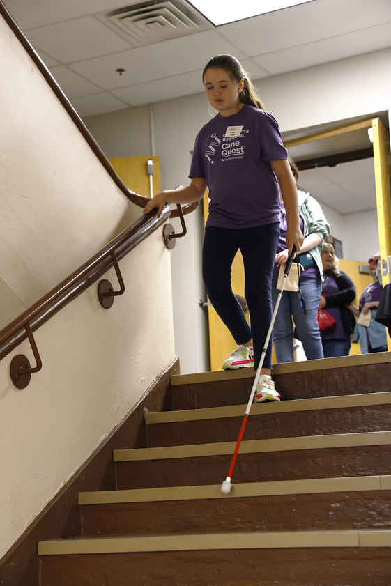Girl with cane going down stairs.