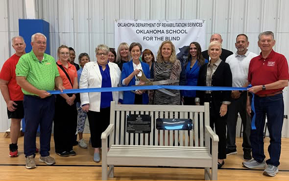 Group of people standing near park bench.