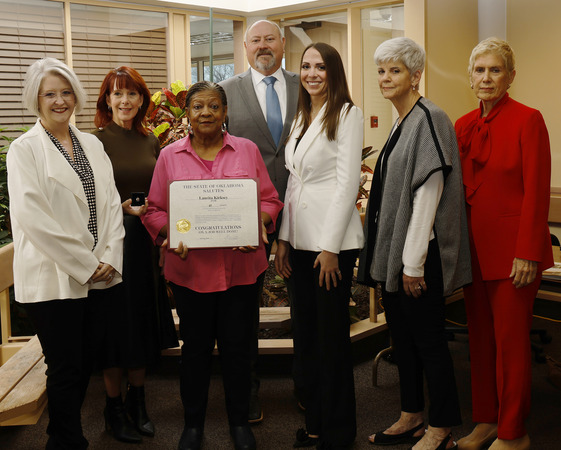 Seven people with one holding a certificate.