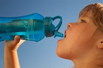 little girl drinking from a blue water bottle