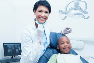 Smiling female hygienist examining boy's teeth