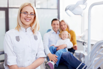 Family in dentist's office with dental professional smiling in foreground