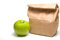 A bag lunch with a Granny Smith apple.