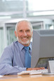 Smiling businessman works on his computer as he sits at his desk.