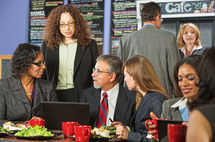 Four business people meeting with laptop on lunch table in a restaurant