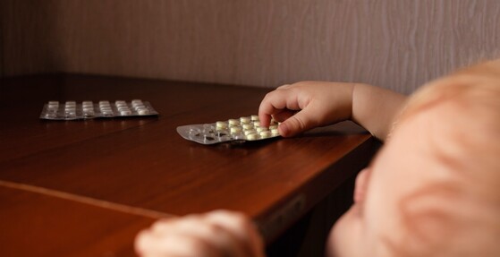 Photo of young child reaching for pills on a table