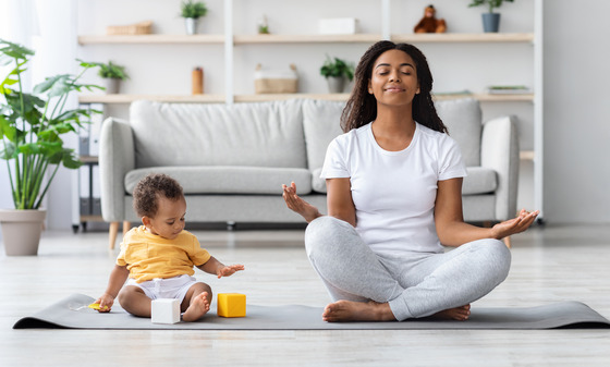 Photo of woman in yoga pose with toddler next to her