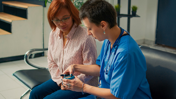 Photo of health care worker checking a female patient's glucose level