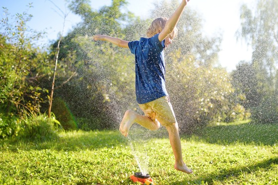 Photo of boy running through sprinkler