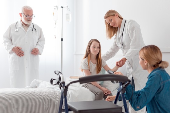 Photo of a child in a hospital bed with a walker nearby