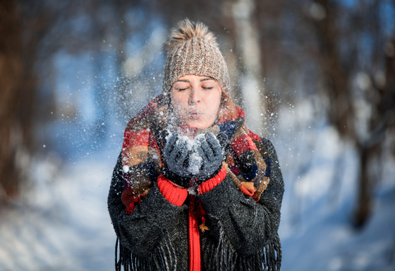 Photo of a woman enjoying the outdoors and blowing snow from her hands