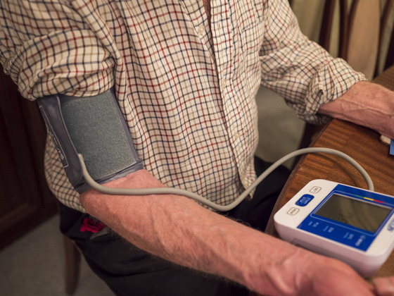 Photo of a man at home checking his blood pressure