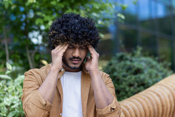 Photo of a man holding his head in pain