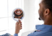 Photo of a man smiling into a mirror