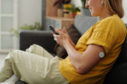 Photo of a woman checking her blood sugar on her continuous glucose monitor