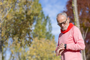 Photo of a senior man checking his watch while out in the park for a walk