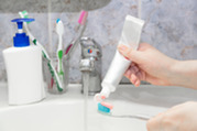 Photo of a woman putting toothpaste on a toothbrush
