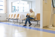 Photo of a senior woman sitting in the waiting room of a medical facility