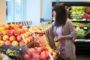 Photo of a woman picking out produce in a grocery store