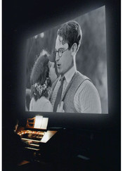 Clark Wilson plays the organ as Girl Shy silent film is seen on screen above