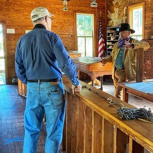 A visitor having a conversation with a reenactor in the original Land Office building located at the Cherokee Strip Regional Heritage Center