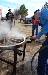 Blacksmith sets a ring in place onto a wooden wagon wheel