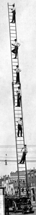 six firemen standing on the rungs of a 40 foot ladder