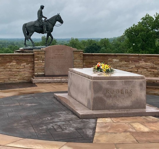Will Rogers tomb with a wreath laid on top and the sculpture of Will Rogers on horseback in the background