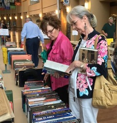 Research Center Book Sale with people at tables of books, opening, reading, and looking at the items on sale at the OHC
