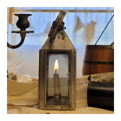 An image of a candle, lit inside a metal lantern