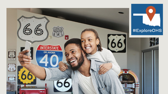 #ExploreOHS contest graphic with an image of a father and child posing for a selfie at the Route 66 Museum in Clinton