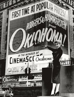 A woman pointing toward the marquee of the film debut of "Oklahoma!" noting that the sign was misspelled "Oklohoma!"