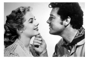 A photos of actors Shirley Jones and Gordon MacRae face to face. This is a promotional image with MacRae holding Jones's chin