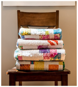 Three folded quilts stacked on a chair