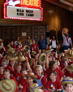 A group of Wild West Kids Camp campers wave their cowboy hats in the air