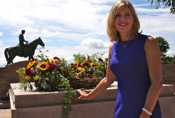 Jennifer Rogers Etcheverry stands beside the Will Rogers Memorial statue, with a commemoration wreath