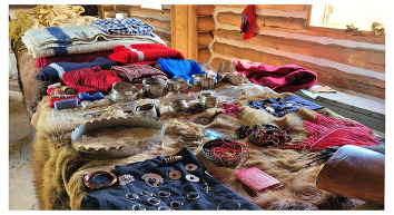 Silver wrist and arm bands, blankets, hides, earrings, and 19th century trading goods are situated on an animal hide at Fort Gibson
